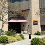 The front of the building where Evolve Dental Care is located on Three Chopt Road. It is a brown building with an orange and brown sign that says Tuckahoe Building.